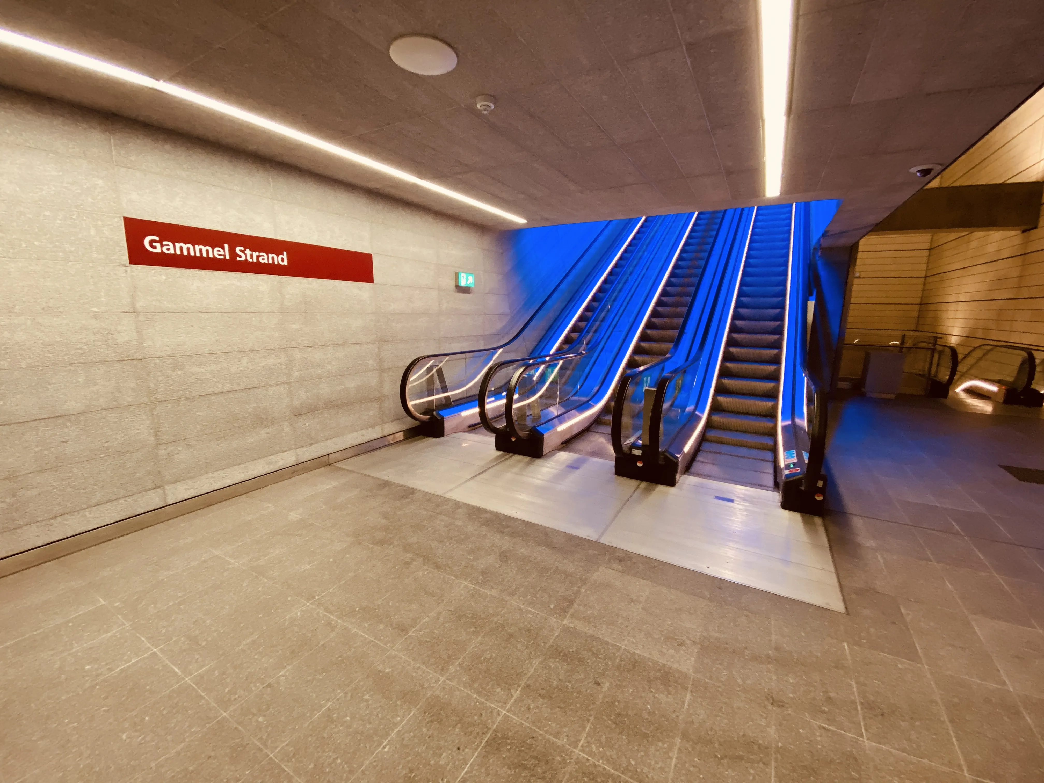 Billede af Gammel Strand Metrostation med et blåt lysspil, som er en hilsen til sollyset i vandoverfladen i Gammel Strands kanal, der løber lige ved siden af stationen. Billede af Gammel Strand Metrostation med et blåt lysspil, som er en hilsen til sollyset i vandoverfladen i Gammel Strands kanal, der løber lige ved siden af stationen.