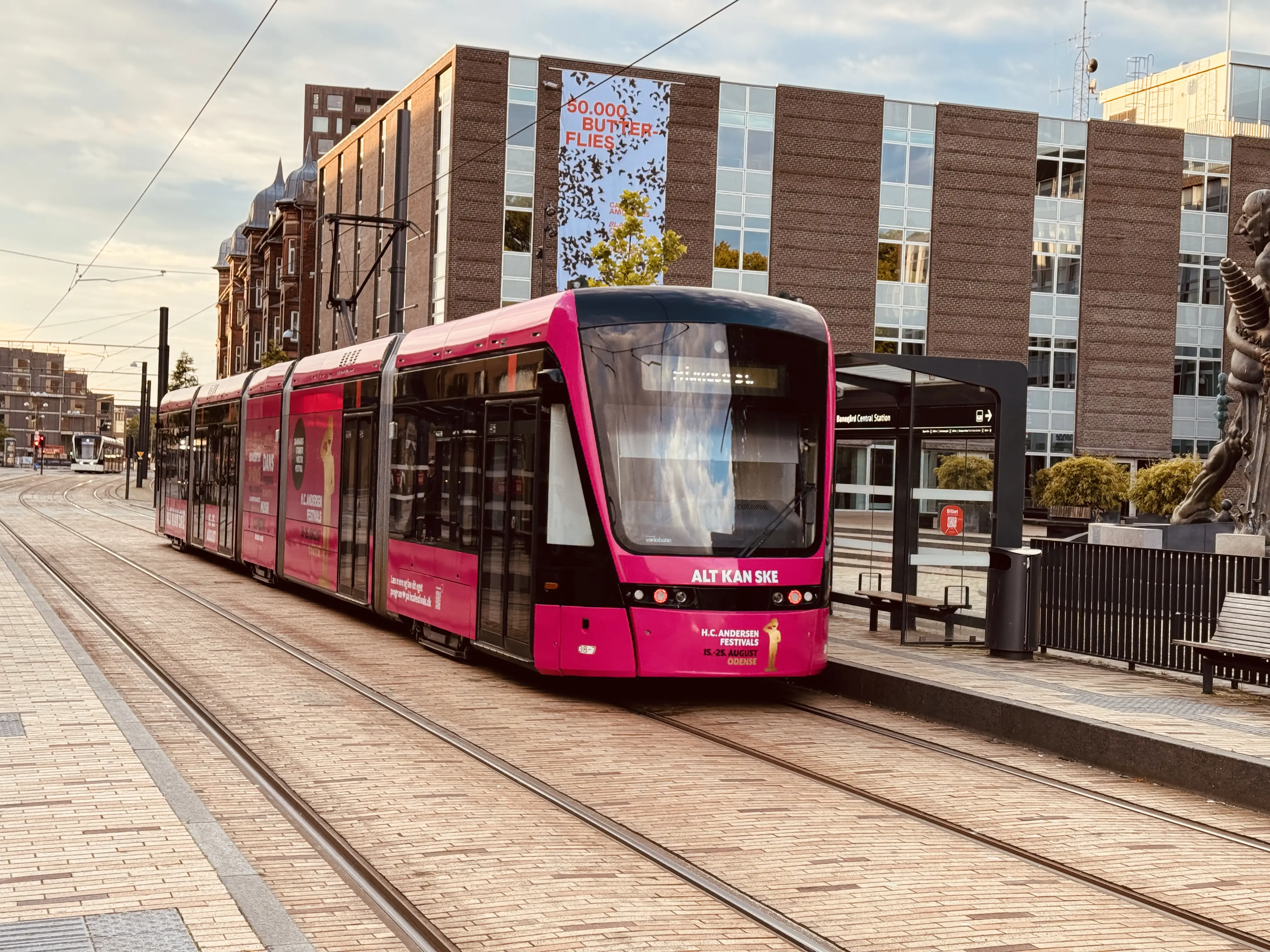 Billede af Odense Letbane togsæt 08, i H.C. Andersen Festivals udklædning, fotograferet ud for Odense Banegård Center. Billede af Odense Letbane togsæt 08, i H.C. Andersen Festivals udklædning, fotograferet ud for Odense Banegård Center.